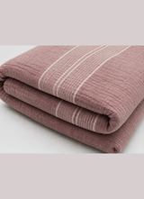 The Summerlight muslin bedding in Antique Blush folded flat, showing the fine white stripe across the crinkled cotton