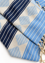 Close-up of the Tessera Aegean Blue weave: yarn-dyed stripes, woven mosaic triangles and cotton tassels